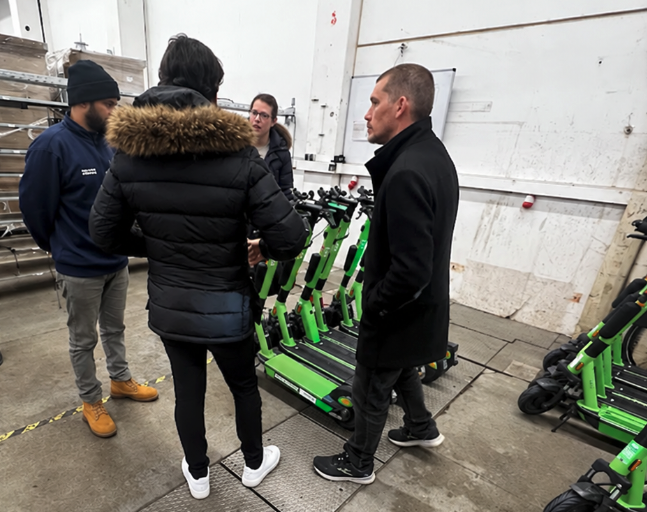 A Fleetser technician walking a fleet of e-scooters with the seller in their warehouse